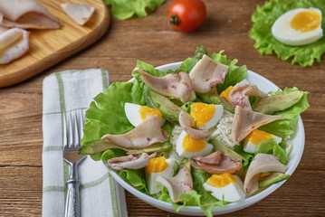 Salad of squid with egg and fresh vegetables on a wooden background