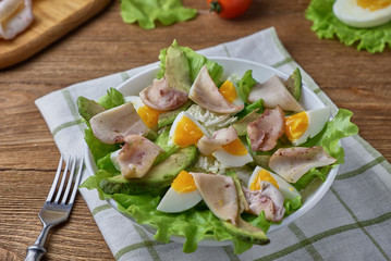 Salad of squid with egg and fresh vegetables on a wooden background