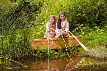 Cute little girls having fun in a boat by a river