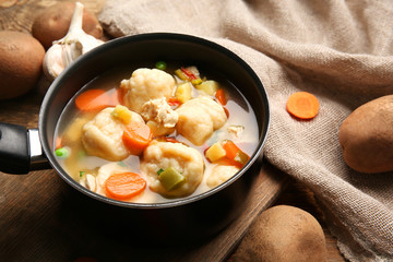 Stewpan with delicious chicken and dumplings on table