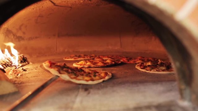 peel placing pizza baking in oven at pizzeria