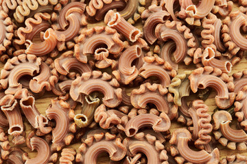 Dry colored italian pasta on a wooden table