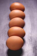 Row of brown eggs on black background. Vertical shoot.