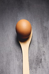 Brown egg on a wooden spoon.