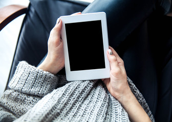 A girl holding a tablet in hands, reader with a nice manicure. Leather trousers, ugg boots. Fashion, style, learning, modern, recreation
