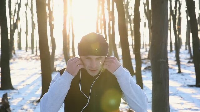 Young runner with headphones in the park at sunset. Winter training for recuperation