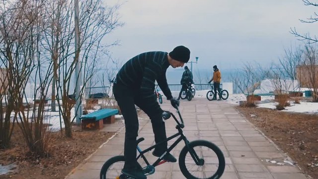 Teenager rides the BMX and does tricks and jumps in the winter park. Slow motion. 120 fps.
