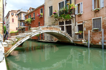 Fototapeta na wymiar Venetian stone bridge. View of one of the typical canals and houses of the famous city of Venice.