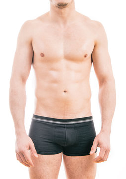 Muscular young man wearing boxer briefs isolated on white background.