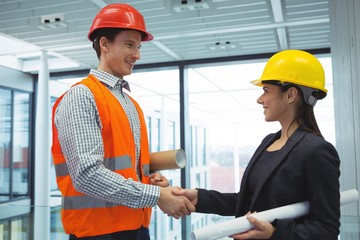 Male architect shaking hands with businesswoman