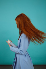 Side view of ginger woman in bathrobe holding book