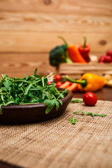 Arugula leaves in bowl. Fresh salad. Natural raw vegetables. Organic bio food on rustic wooden table.