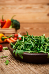 Arugula leaves in bowl. Fresh salad. Natural raw vegetables. Organic bio food on rustic wooden table.