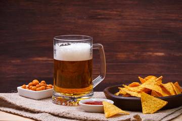 Glass of beer. Nachos chips. Tortilla snack. Mexican salsa nuts. Appetizer with sweet salsa or chilli sauce. Mug or pint of ale. On rustic wooden background.