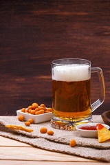 Glass of beer. Nachos chips. Tortilla snack. Mexican salsa nuts. Appetizer with sweet salsa or chilli sauce. Mug or pint of ale. On rustic wooden background.