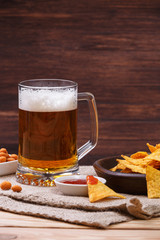 Glass of beer. Nachos chips. Tortilla snack. Mexican salsa nuts. Appetizer with sweet salsa or chilli sauce. Mug or pint of ale. On rustic wooden background.