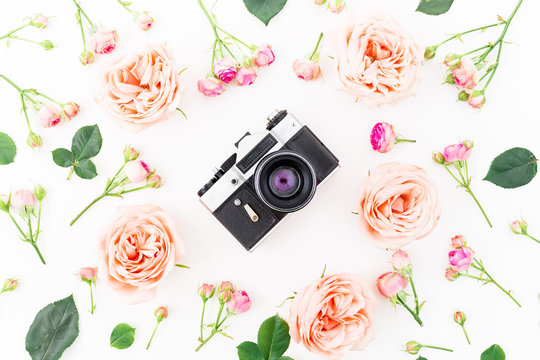 Round frame with pink roses and Old camera on white background. Flat lay, top view. Floral background.