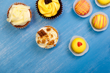 Cupcakes with buttercream and macaroons. Almond macaron cookies. Sweet dessert cakes. On wooden table.