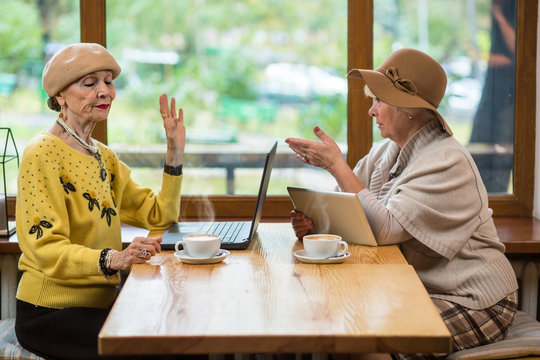 Women with gadgets in cafe. Coffee cups, laptop and tablet. Pros and cons of internet.
