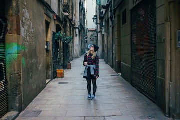 trendy hipster flannel shirt and beanie exploring the city in alley on way to university