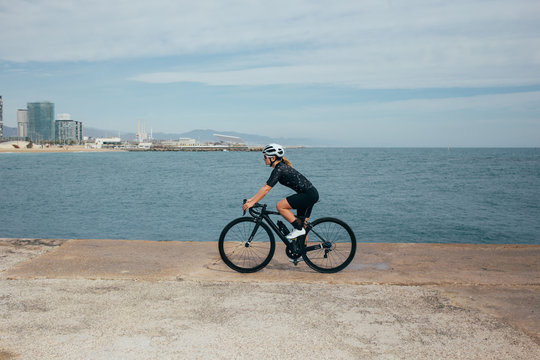 Female professional cyclist spins on pier in nice light by the seaside