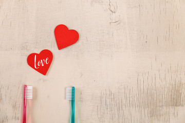 Love concept with hearts and toothbrushes. Love text. Valentines day design on wood vintage background. Wooden rustic board.
