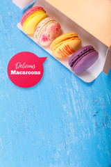 Macaroon cakes. Colored almond macaron cookies. Delivery box. Different flavors. On blue wooden rustic background.