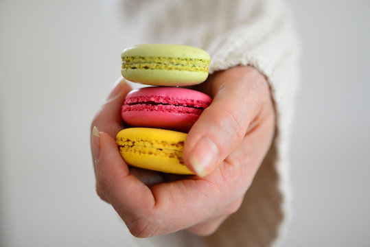 Close-up of a Woman's hand holding three different flavoured macarons (french macaroons)