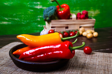 Peppers in bowl. Cherry tomatoes, garlic and potatoes. Fresh natural food. Organic vegetables on wooden table with sackcloth.