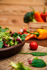 Provence salad. Leaves of endive or chicory, lamb and rose salad. Cherry tomato, pepper and carrot. Raw vegetables. On wooden table.