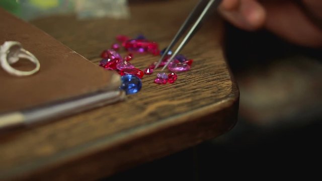 Precious stones on a wooden table and selection of the necessary sample for a silver ring.