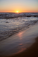 Fototapeta na wymiar Sunrise reflection on beach sand
