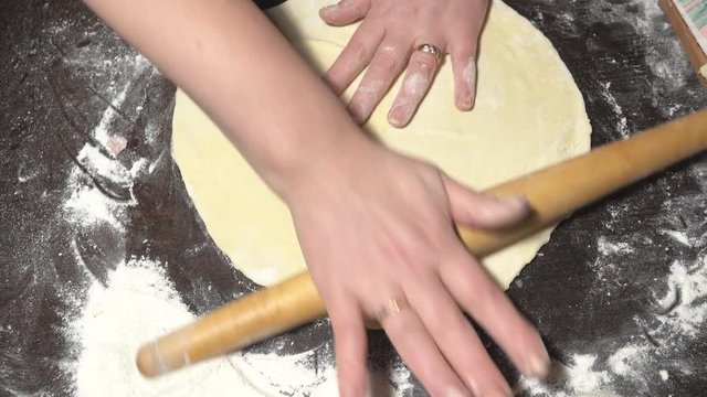 Female hands cut off round dough pieces on a table. Preparation of dough for dumplings. Traditional Ukrainian cuisine