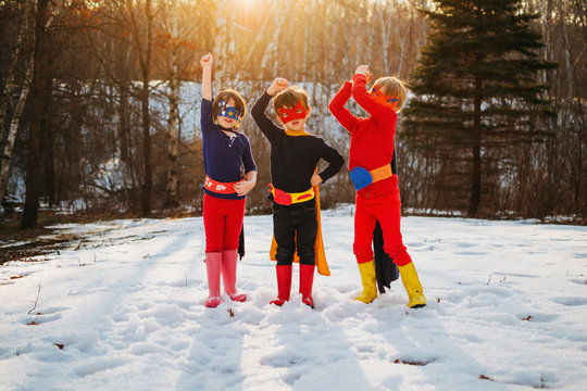 Siblings in superhero costumes posing in winter