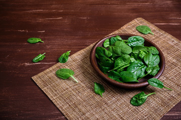 Spinach leaves in bowl. Raw fresh vegetable. Fresh natural plant leaf. Organic bio food on rustic wooden table.