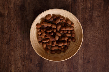 Sweet tamarind on grunge rustic wood background. Natural organic diet food with a lot of vitamins. Plate dish or bowl on wooden board.