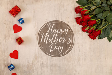 Red roses with hearts on wood background. Love design. Happy Mothers day concept. Fresh natural flowers with gift boxes. Wooden rustic board.