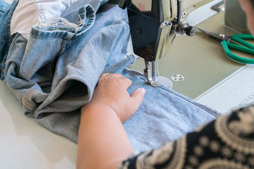 woman Hands of Seamstress Using Sewing Machine tailor - Sewing Machine and Jeans.