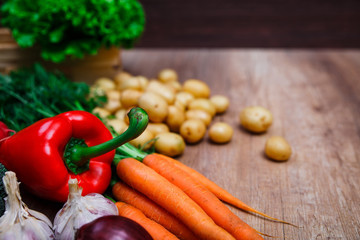 Vegetables. Potatoes, carrot and red pepper. Lettuce salad, garlic and onion. Natural organic bio food. Wooden basket on rustic table.