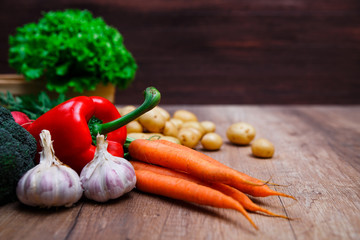 Vegetables. Potatoes, carrot and red pepper. Lettuce salad and garlic. Natural organic bio food. Wooden basket on rustic table.