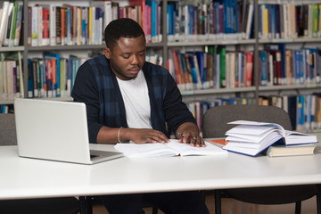 Young Student Using His Laptop In A Library