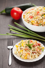 Tabbouleh salad with couscous, tomatoes, onion, zucchini and bell peppers topped with basil leaf far away shot