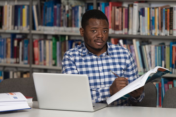 Young Student Using His Laptop In A Library