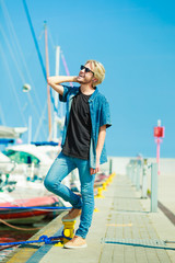 Blonde man standing near harbor in summer