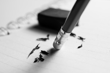 Fototapeta premium pencil eraser removing a written mistake on a piece of paper, delete, correct, and mistake concept.