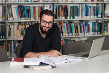 Happy Male Student With Laptop In Library