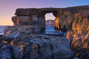 Azure window, natural stone arch by Dwejra cliffs on a sunset