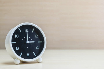 Closeup alarm clock for decorate in 3 o'clock on brown wood desk and wall textured background with copy space