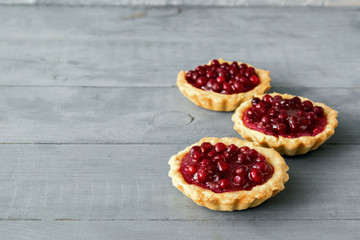 Small fresh red berry tartlets stuffed gray background