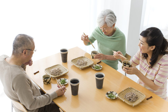 Family eating soba noodles, smiling